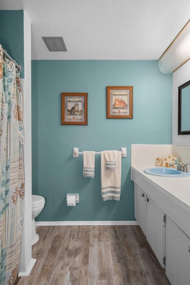 8021 Wildflower Row, Hudson, FL 34667 - full bathroom featuring wood finished floors, vanity, toilet, baseboards, and a shower with curtain