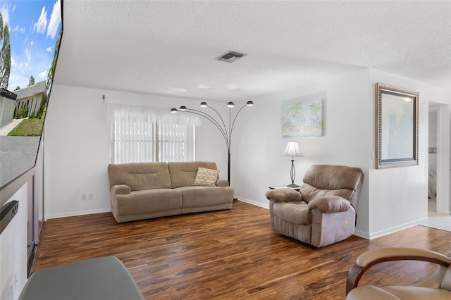 living room featuring a textured ceiling, wood finished floors, and baseboards