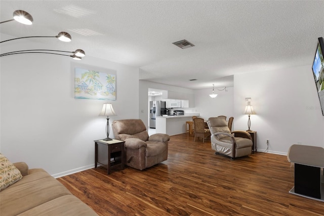 living room with dark wood-type flooring, baseboards, and a textured ceiling