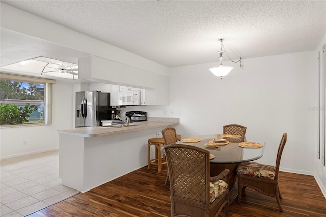dining area featuring a textured ceiling, ceiling fan, baseboards, and wood finished floors