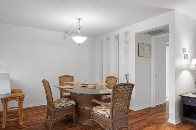 dining area with wood finished floors, baseboards, and a textured ceiling