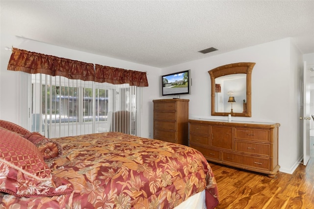 bedroom with a textured ceiling and light wood-style floors