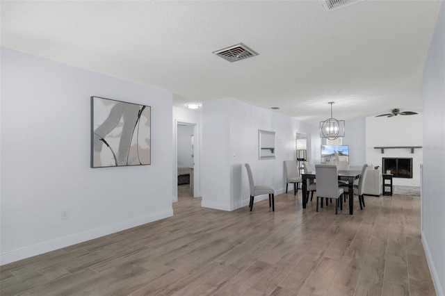 7520 Mako Dr, Hudson, FL 34667 - dining room featuring light wood finished floors, baseboards, a chandelier, and a fireplace
