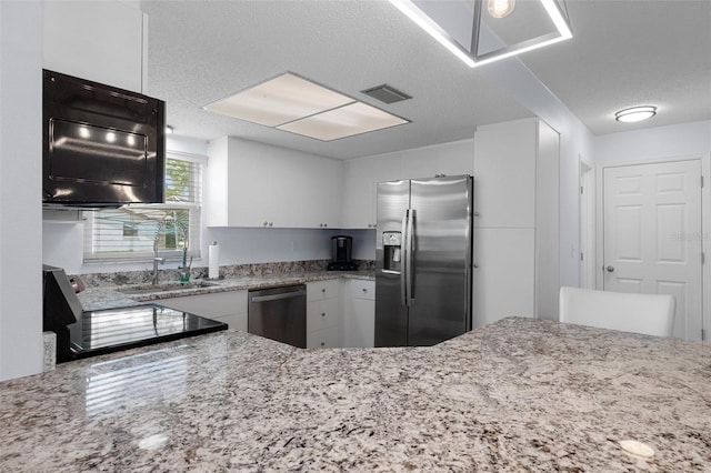 7520 Mako Dr, Hudson, FL 34667 - kitchen featuring appliances with stainless steel finishes, a sink, white cabinets, light stone countertops, and a textured ceiling