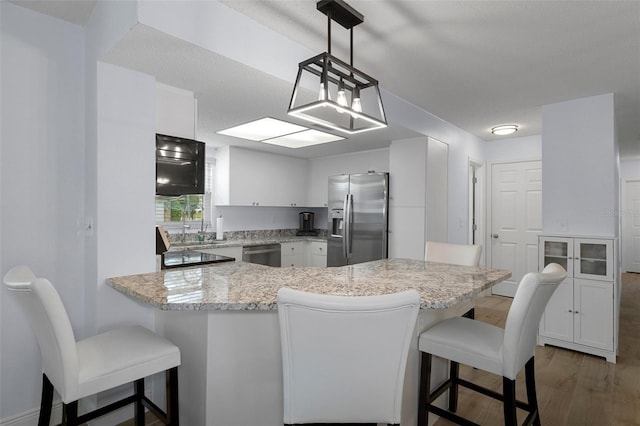 7520 Mako Dr, Hudson, FL 34667 - kitchen featuring stainless steel appliances, white cabinetry, a breakfast bar, dark wood-style floors, and light stone counters