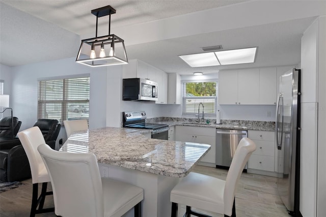 7520 Mako Dr, Hudson, FL 34667 - kitchen with stainless steel appliances, a sink, a peninsula, white cabinetry, and a kitchen breakfast bar
