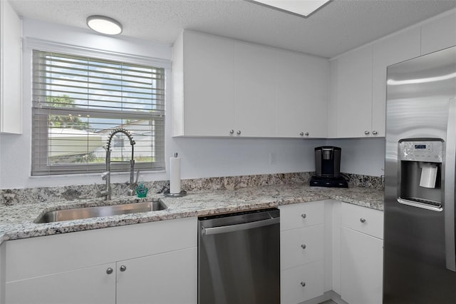 7520 Mako Dr, Hudson, FL 34667 - kitchen with stainless steel appliances, a sink, a textured ceiling, and white cabinetry