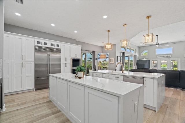 kitchen featuring appliances with stainless steel finishes, an island with sink, recessed lighting, white cabinets, and ceiling fan