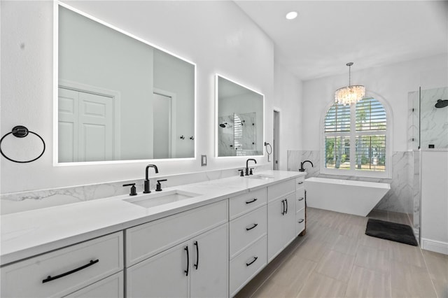 bathroom with a marble finish shower, double vanity, a chandelier, tile walls, and a soaking tub