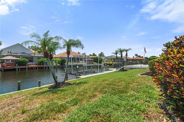 view of grassy yard featuring boat lift, a boat dock, and a water view