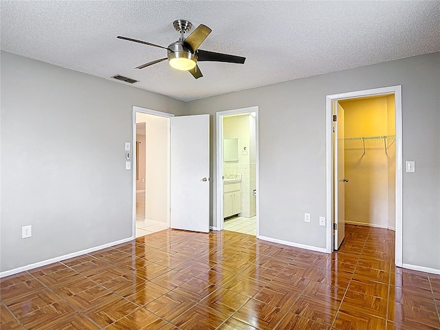 13003 Sandburst Ln, Hudson, FL 34667 - unfurnished bedroom featuring a spacious closet, a closet, baseboards, a textured ceiling, and ensuite bath