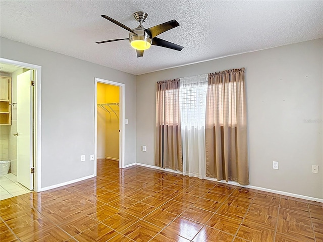 13003 Sandburst Ln, Hudson, FL 34667 - unfurnished bedroom featuring a textured ceiling, a walk in closet, baseboards, a closet, and ensuite bathroom