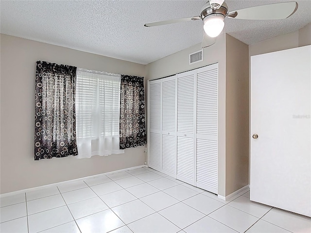 13003 Sandburst Ln, Hudson, FL 34667 - unfurnished bedroom with a closet, a textured ceiling, light tile patterned floors, a ceiling fan, and baseboards