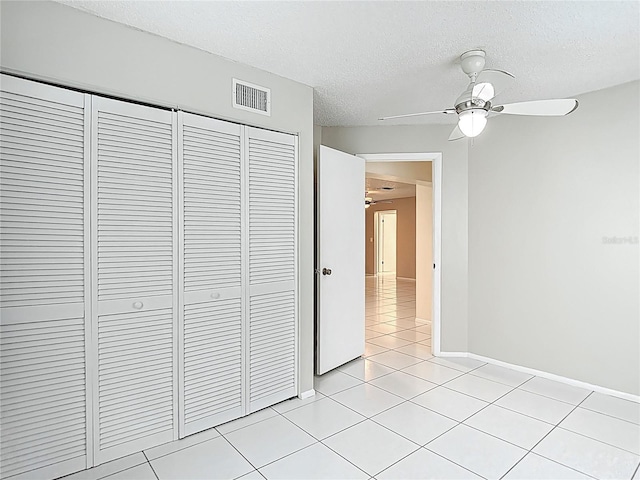 13003 Sandburst Ln, Hudson, FL 34667 - unfurnished bedroom with a closet, a textured ceiling, light tile patterned floors, baseboards, and ceiling fan