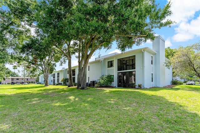 306 Martha Ln Unit 42, Oldsmar, FL 34677 - back of property featuring a yard, a chimney, central air condition unit, and stucco siding