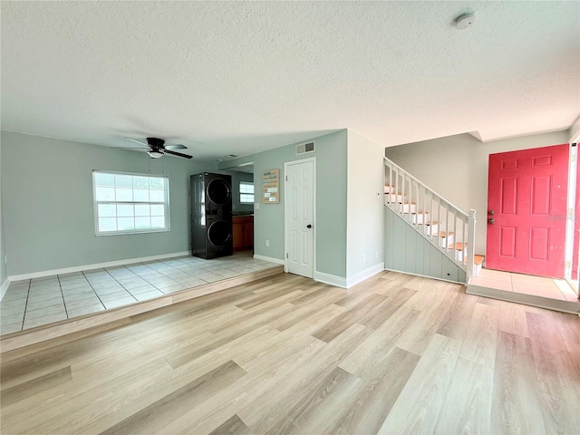 unfurnished living room with wood finished floors, stairs, a textured ceiling, a ceiling fan, and baseboards
