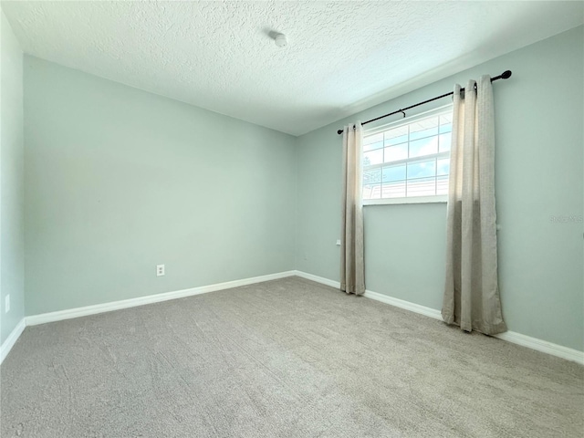 carpeted empty room with a textured ceiling and baseboards