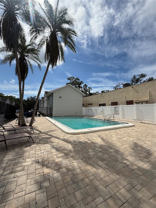 community pool featuring fence and a patio