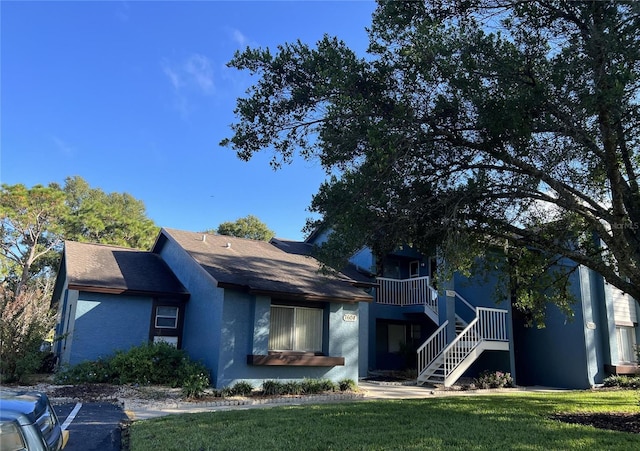 7600 St Andrews Blvd Unit 7600, Weeki Wachee, FL 34613 - view of front of property with stucco siding, a front yard, stairway, and roof with shingles