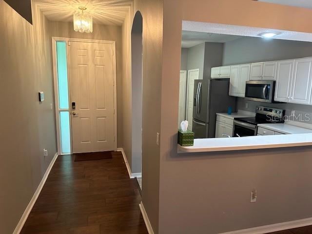 20720 Eustis Rd, Land O Lakes, FL 34637 - kitchen with appliances with stainless steel finishes, white cabinets, light countertops, dark wood finished floors, and arched walkways