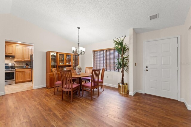 7512 Heather Walk Dr, Weeki Wachee, FL 34613 - dining area featuring light wood-style floors, a chandelier, vaulted ceiling, and a textured ceiling