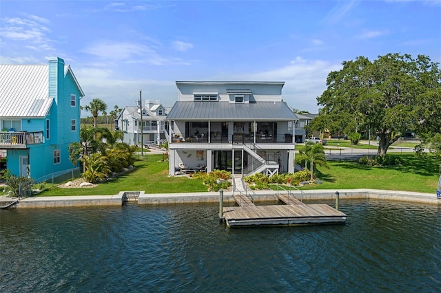 rear view of property with stairway, a water view, a lawn, and metal roof