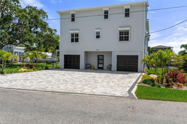 view of front of property featuring a garage, decorative driveway, and fence