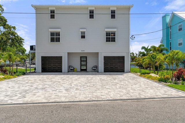 coastal home with a garage, fence, and driveway