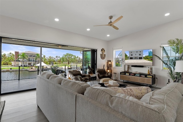 living room featuring ceiling fan, recessed lighting, wood finished floors, and a water view