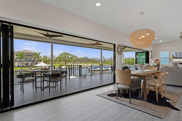 dining room with ceiling fan, healthy amount of natural light, wood finished floors, recessed lighting, and a water view