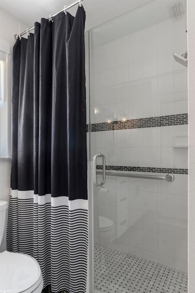 bathroom featuring toilet and a stall shower