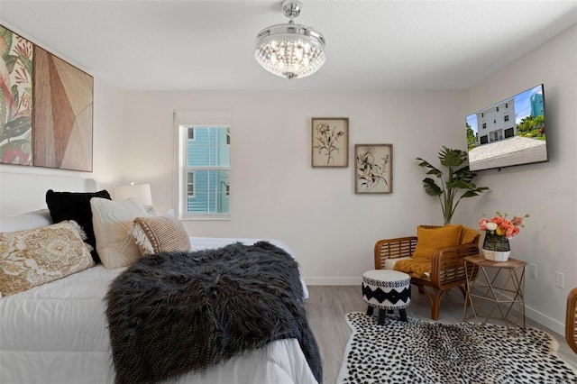 bedroom with a chandelier, wood finished floors, and baseboards