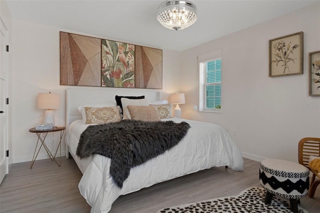 bedroom featuring wood finished floors, a chandelier, and baseboards