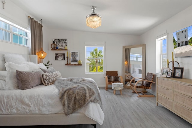 bedroom with multiple windows, light wood-type flooring, baseboards, and a chandelier