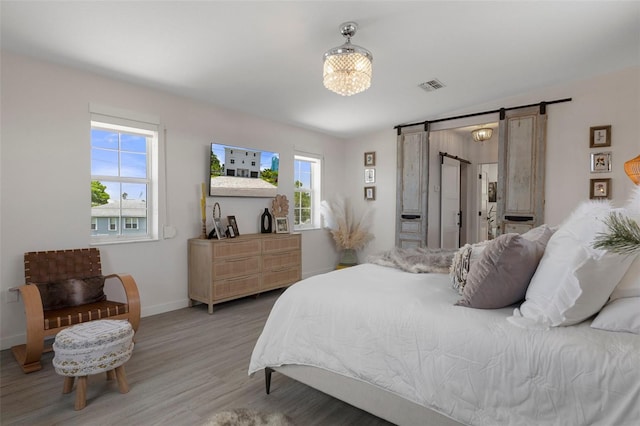bedroom featuring a barn door, wood finished floors, and baseboards
