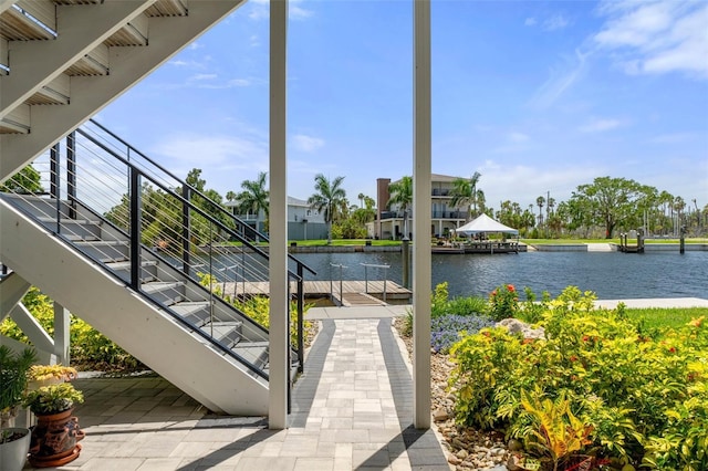 view of patio with a water view, stairway, and a boat dock