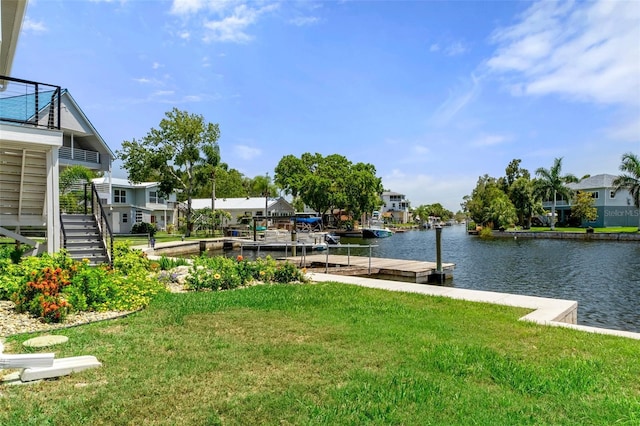 view of green lawn with a floating dock, a water view, stairway, and a residential view
