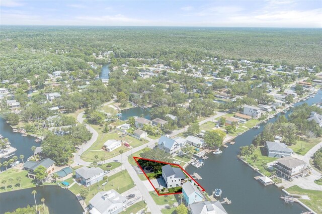 aerial perspective of suburban area with a forest, property boundaries highlighted, and a large body of water