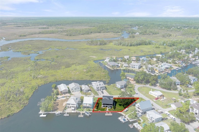 aerial view of residential area featuring property parcel outlined, a nearby body of water, and a forest