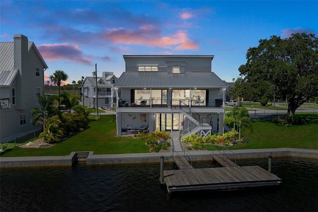 5234 Foxhall Ct, Weeki Wachee, FL 34607 - back of house at dusk featuring stairway, a lawn, metal roof, and a water view