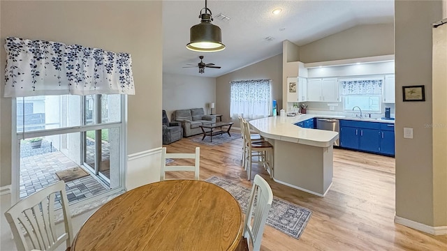 kitchen featuring blue cabinets, a peninsula, healthy amount of natural light, light countertops, and high vaulted ceiling