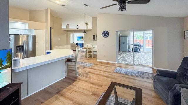 living room with ceiling fan, light wood-type flooring, baseboards, and high vaulted ceiling