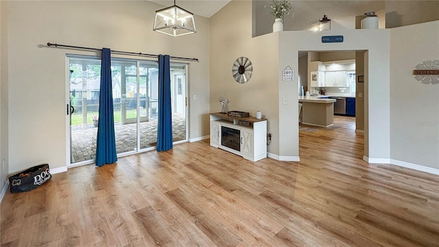 entryway featuring high vaulted ceiling, baseboards, a chandelier, and light wood finished floors