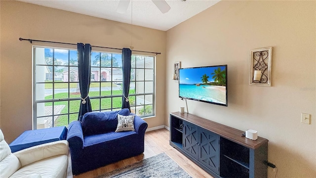 living area with light wood-style floors, ceiling fan, plenty of natural light, and baseboards