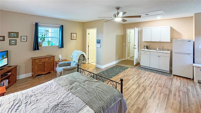 bedroom featuring freestanding refrigerator, light wood-style floors, baseboards, a sink, and a ceiling fan