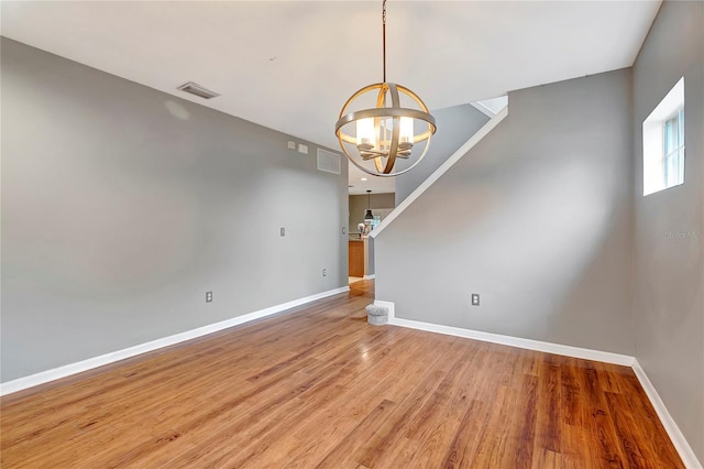 unfurnished dining area featuring a chandelier, baseboards, and wood finished floors