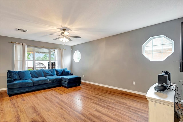 living area with baseboards, ceiling fan, and light wood-style flooring