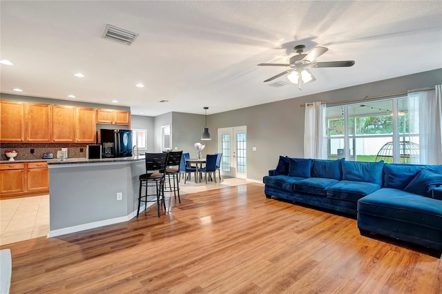 living room featuring light wood-style flooring, plenty of natural light, a ceiling fan, and recessed lighting