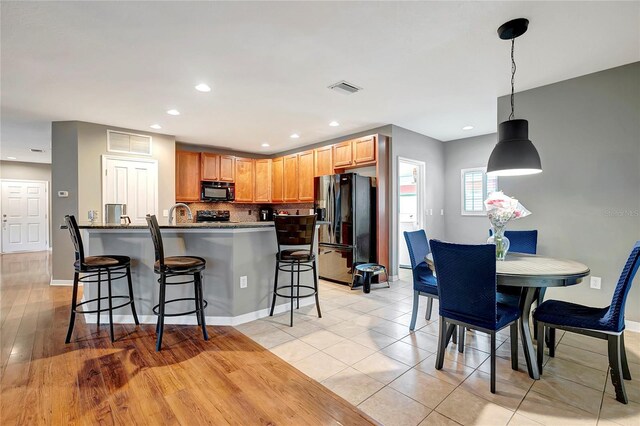 kitchen with black appliances, a kitchen bar, tasteful backsplash, recessed lighting, and pendant lighting