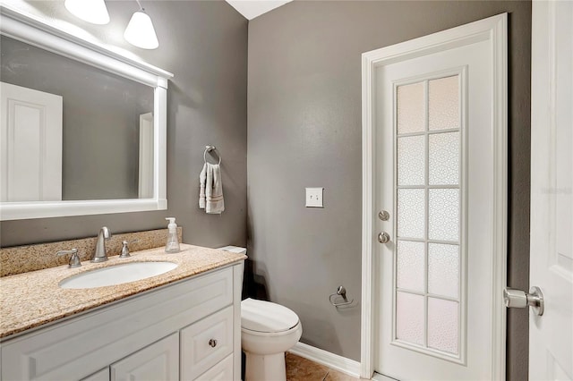 bathroom featuring toilet, vanity, tile patterned flooring, and baseboards